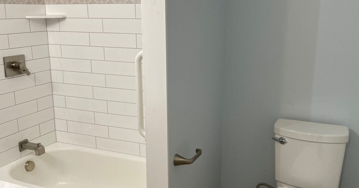 Completed bathroom remodel by AFGH Handyman with a white subway tile tub surround and new fixtures