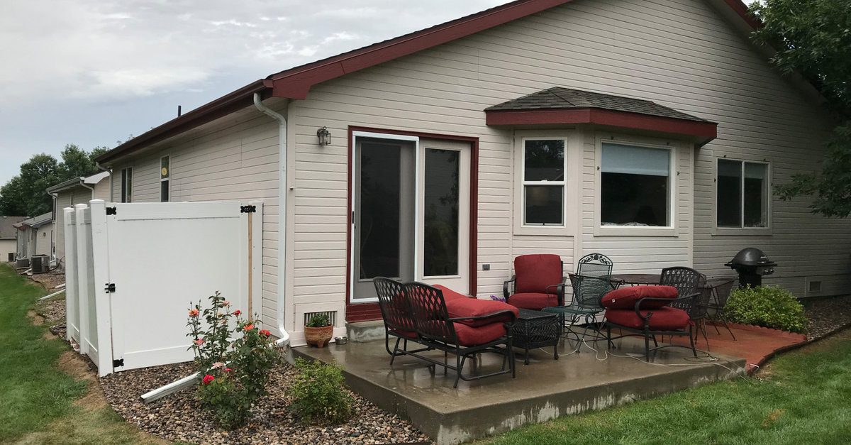 White vinyl privacy fence and gate installed by AFGH Handyman beside a patio on an exterior project