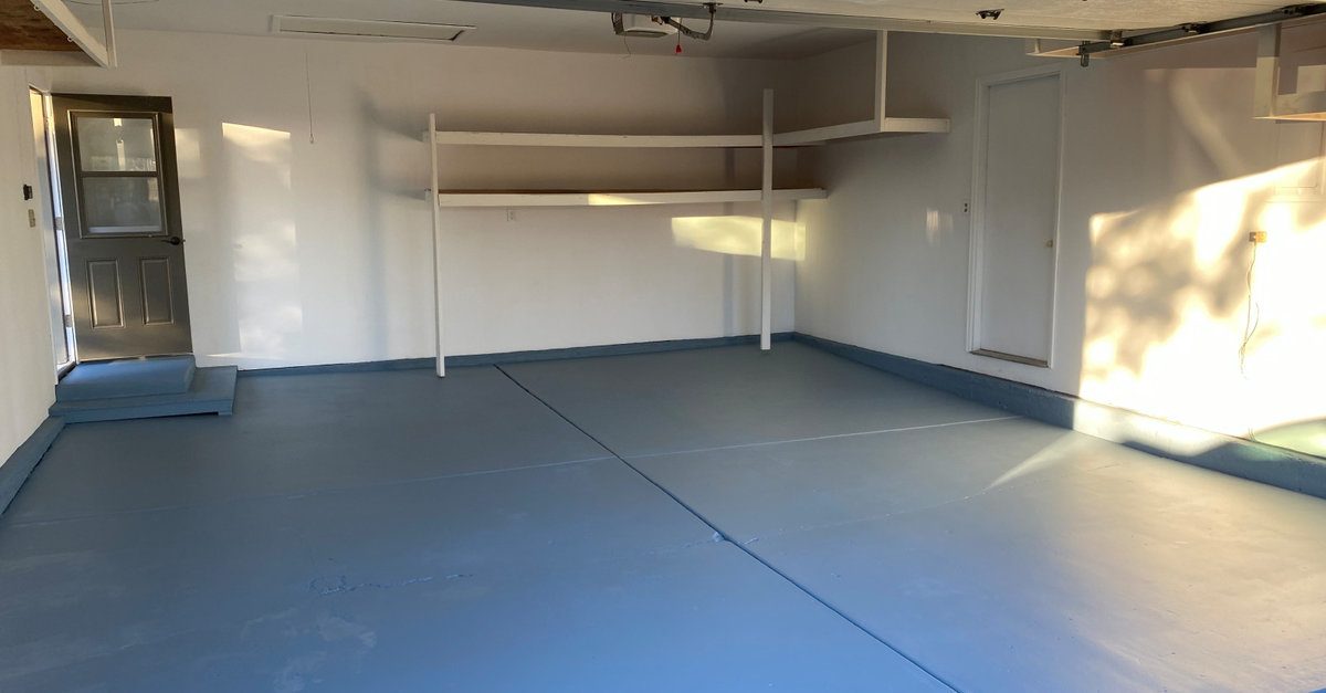 Freshly painted garage interior with white walls, blue floor coating and custom shelving by AFGH Handyman in Erie, CO