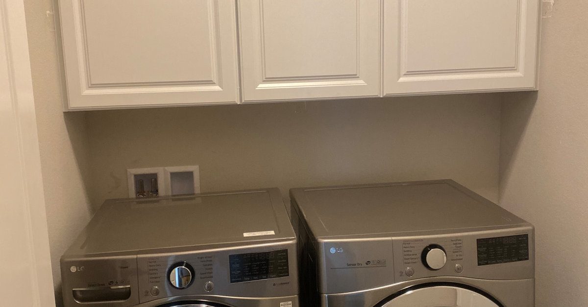 Laundry room remodelled by AFGH Handyman with new white overhead cabinets above the washer and dryer