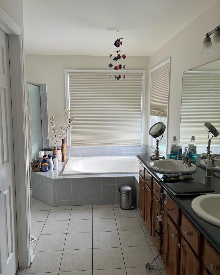 Master bathroom with a dated tiled tub deck and oak vanity before an AFGH Handyman remodel